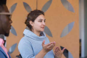 Focused excited female entrepreneur explaining startup details to colleagues. Young woman in casual speaking and gesturing. Startup discussion concept